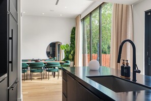 Eine moderne Küche mit einer schwarzen Arbeitsplatte, einem Spülbecken und einem großen Fenster mit Vorhängen.