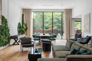 Ein modernes Wohnzimmer mit einem grünen Sofa, einem Esstisch mit Stühlen und einem Billardtisch.