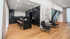 A modern kitchen with a central island, bar stools, and a staircase leading to an upper level. - Eden Luxury in Miami Design District, BBQ & Pool (Miami)