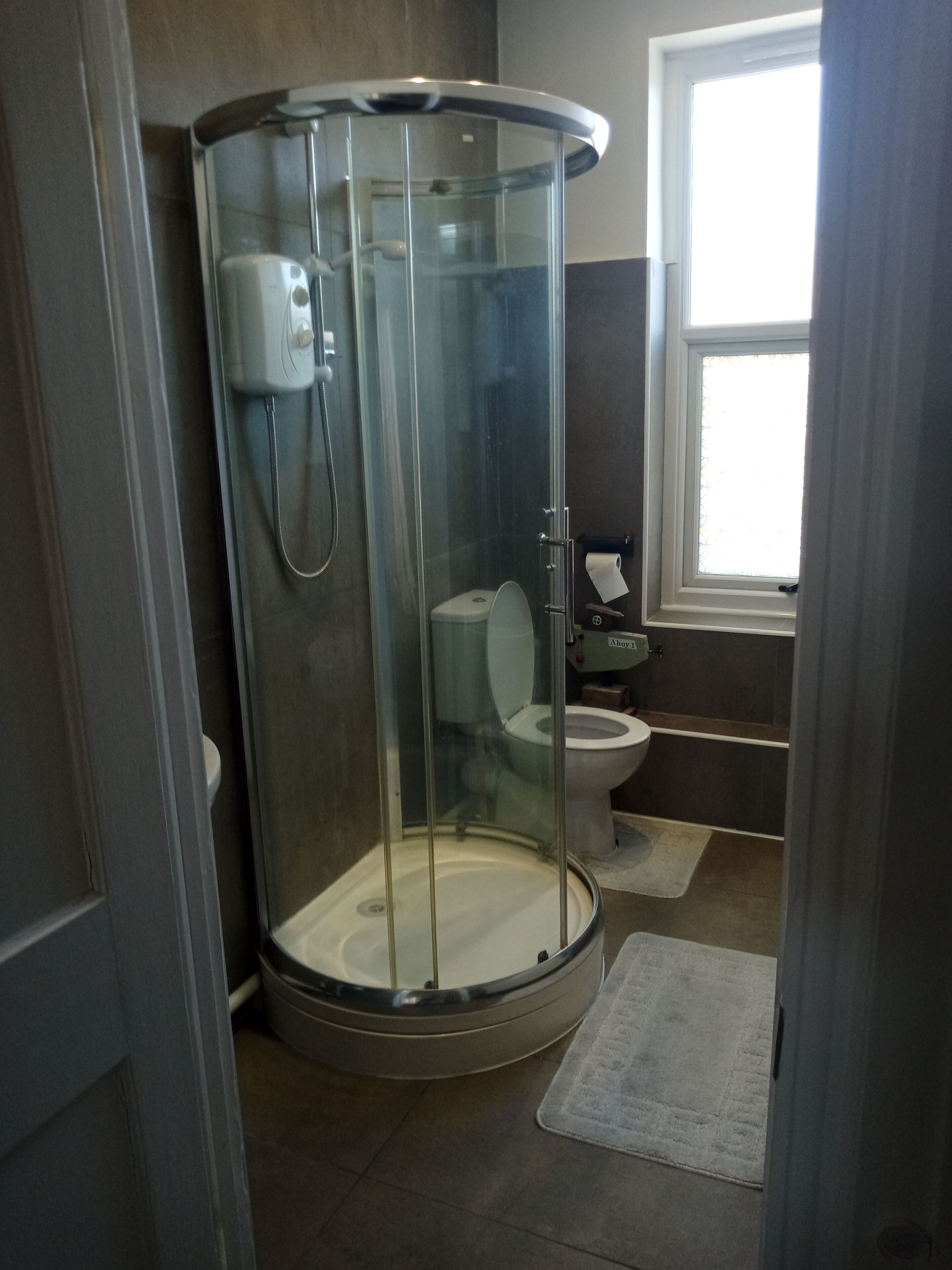 A bathroom with a glass-enclosed shower, a toilet, and a sink.