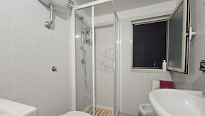 Une salle de bain équipée de toilettes, d’un bidet et d’une douche à parois de verre.