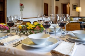 A dining table set with multiple wine glasses, bowls, and cutlery, with a floral centerpiece. - Villa Collegigliato 8, Emma Villas (Pistoia)