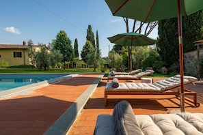 A poolside area with lounge chairs, a pergola, and a stone wall. - Villa Collegigliato 8, Emma Villas (Pistoia)