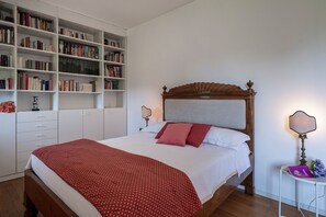 Ein Schlafzimmer mit einem hölzernen Bett, einem Bücherregal und einem Nachttisch mit Lampe.