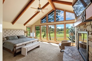 Ein Schlafzimmer mit einem großen Bett, einem Deckenventilator und Blick auf einen Golfplatz durch große Fenster.
