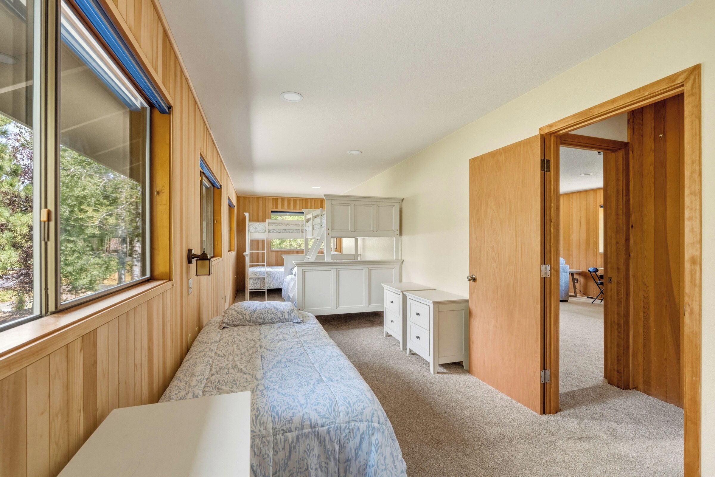 A bedroom with a bunk bed, a desk, and a wardrobe.