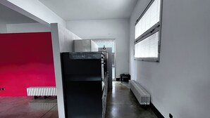 Ein geräumiger Flur mit Kühlschrank, Heizkörper und einem Fenster mit Jalousien.