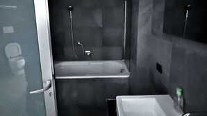 Ein modernes Badezimmer mit Glastür, Badewanne, Dusche und Waschbecken.