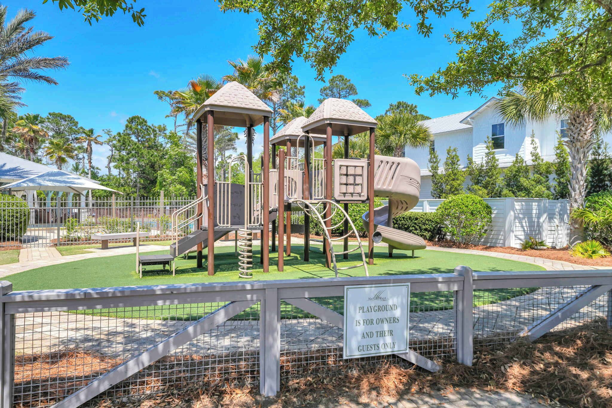 A playground with a play structure, a fenced area, and a sign indicating it is for owners and their guests only.