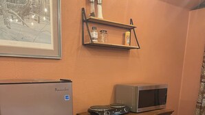 Une cuisine de taille réduite équipée d’un réfrigérateur, d’un four à micro-ondes et d’un meuble en bois.