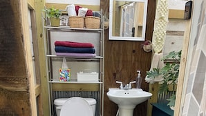 Une petite salle de bain comprenant des toilettes, un lavabo et des étagères de rangement.