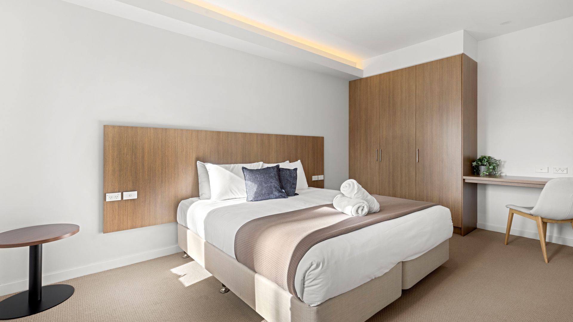 Ein modernes Hotelzimmer mit einem großen Bett, einem Schreibtisch und einem Stuhl.