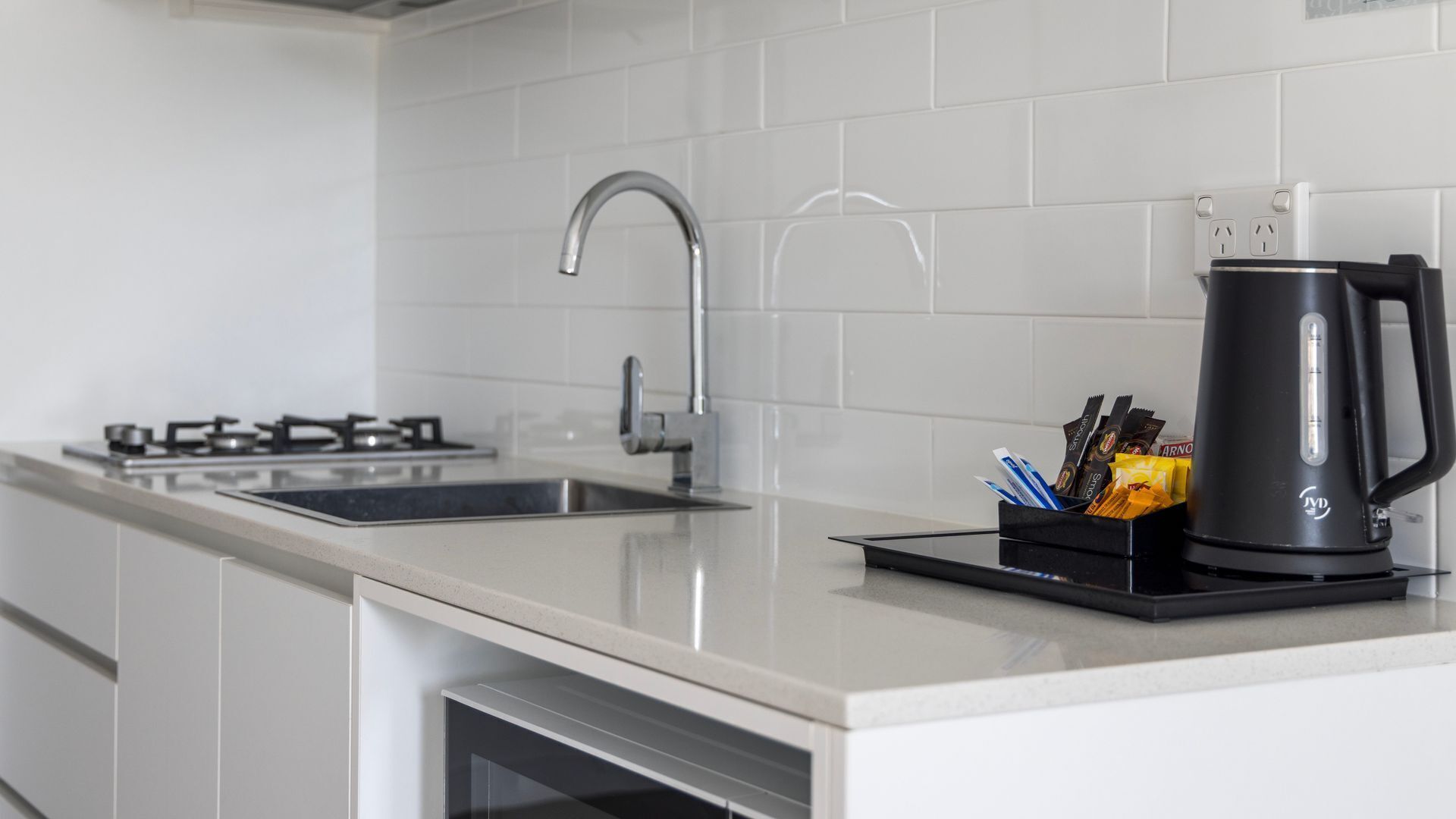 A modern kitchen with a gas stove, stainless steel sink, and a coffee maker on the counter.