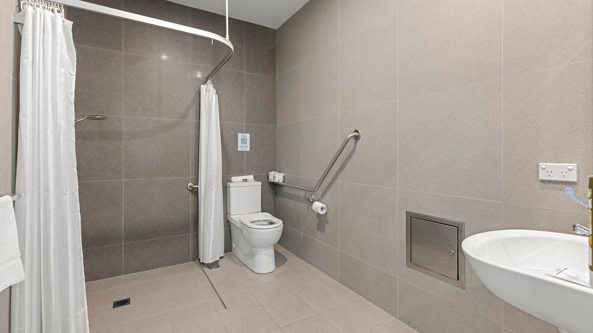 Een moderne badkamer met douche, toilet en wastafel.
