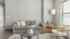 A modern living room with a grey sofa, a round coffee table, a side table, and a chair. - Landing | Incredible 2BD, Clubhouse, Pool (Fort Worth)