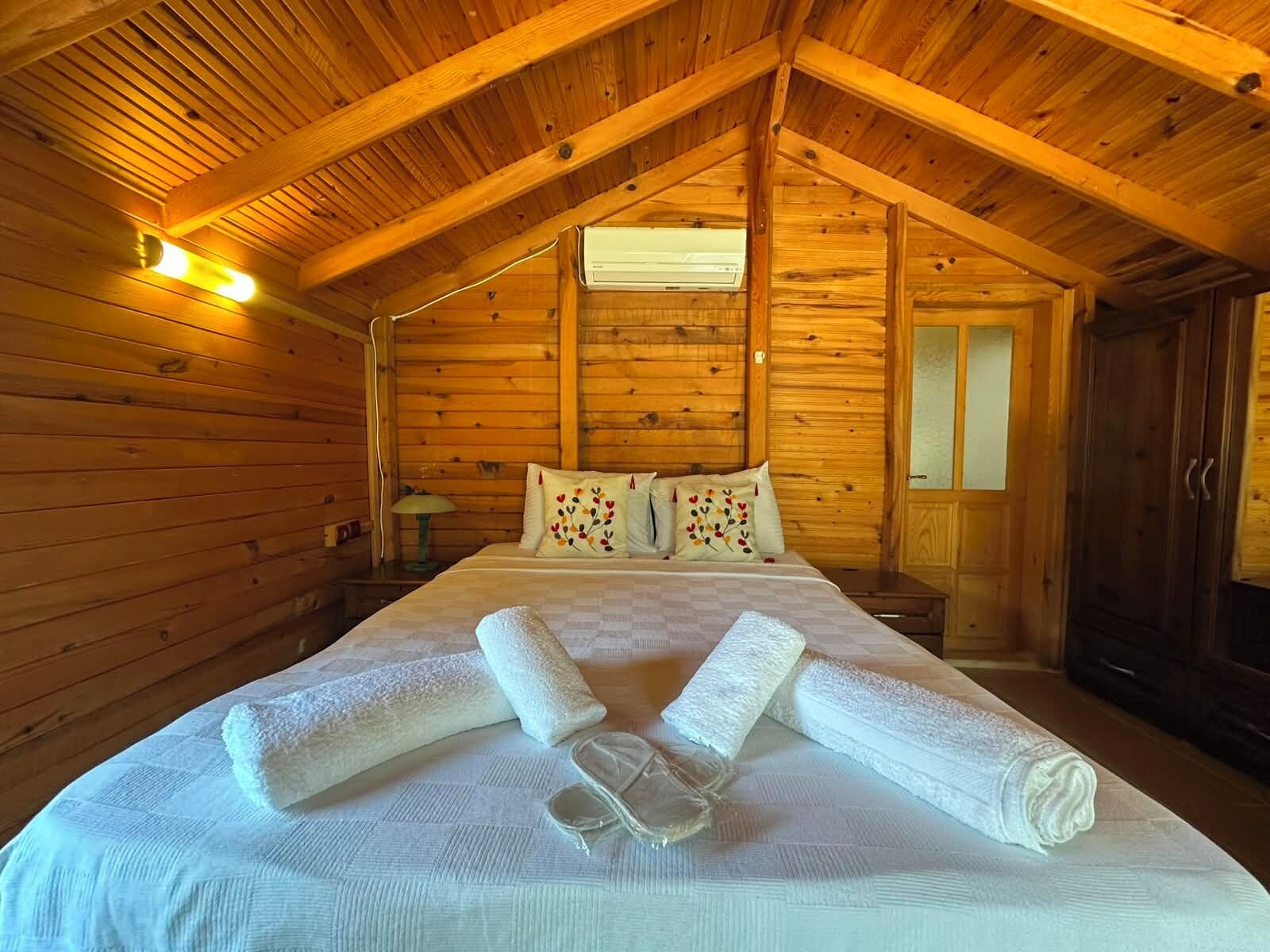 Una habitación de cabaña de madera con una cama, almohadas y toallas.