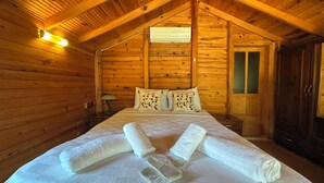 Dormitorio de cabaña de madera con cama, almohadas y toallas.