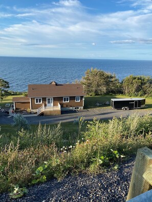 A house with a view of the sea, a driveway, and a trailer.