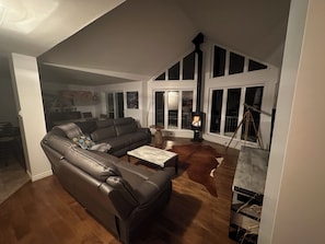 A living room with a leather sofa, a coffee table, a fireplace, and a large window.