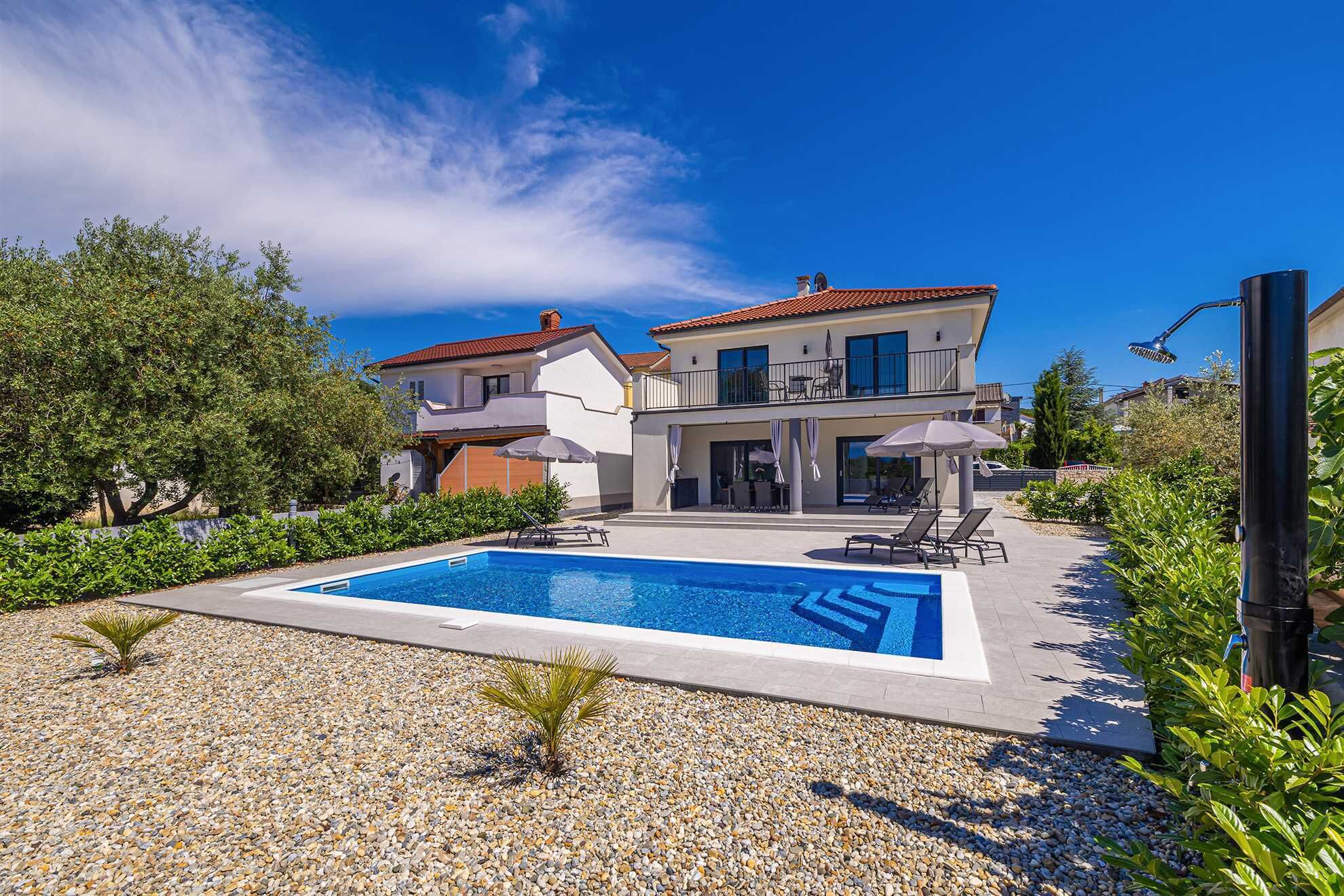 Una casa de dos pisos con piscina y zona de estar exterior.