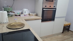 Eine kleine Küche mit Mikrowelle, Backofen und einer Arbeitsfläche.