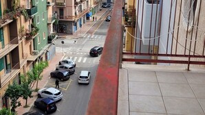En flervåningsbyggnad med bostäder, balkonger, utsikt över gatan och parkerade bilar.