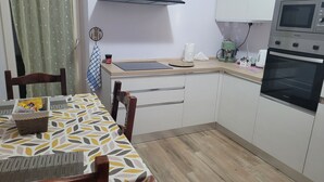 Ett kompakt kök med vita skåp, en bänkskiva, en kaffemaskin och en mikrovågsugn.