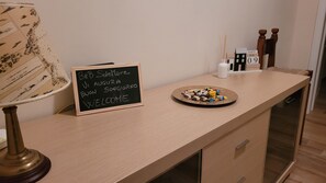 Un comptoir en bois avec un panneau en ardoise, une assiette de collations, une lampe et un calendrier.