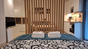Ein Hotelzimmer mit Bett, Fernseher, Küchenzeile und einer Holzwand.
