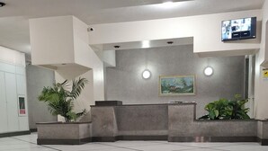 A modern lobby with a reception desk, seating area, and a flat-screen TV mounted on the wall. - Apartment that still smells new,opening in April,20 minutes from the city center (Palermo)
