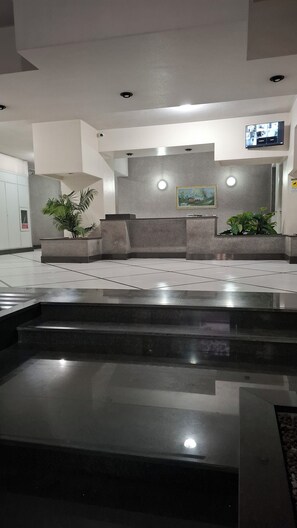 Eine moderne Lobby mit einer Rezeption, einer Sitzecke und einem an der Wand befestigten Flachbildfernseher.