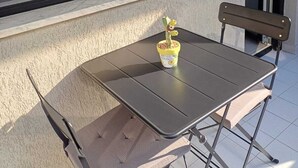 A small outdoor table with a chair, a potted plant, and a window with a view of buildings. - Apartment that still smells new,opening in April,20 minutes from the city center (Palermo)