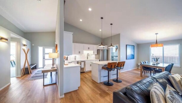 Een moderne keuken met witte kasten, een centraal eiland en hanglampen.