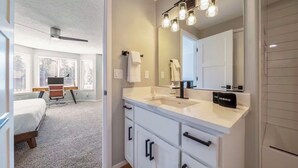 Een moderne badkamer met een grote spiegel, een witte wastafel en een plafondventilator.