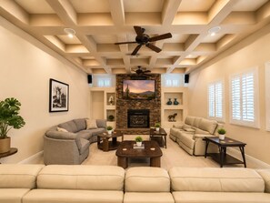 A living room with a fireplace, sofas, a coffee table, and a ceiling fan. - Exquisite 9BR/5BA Villa - Sports Court, Game Room, Movie Room, Pool, & Spa ★★★★★ (North Las Vegas)