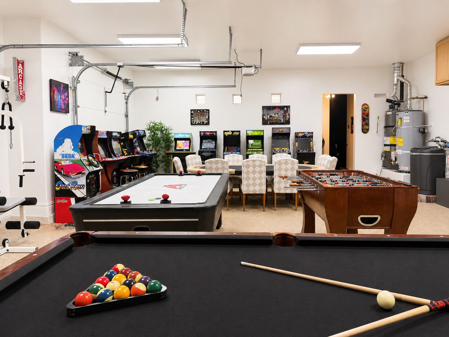 A recreational room with a pool table, foosball table, and multiple arcade machines.