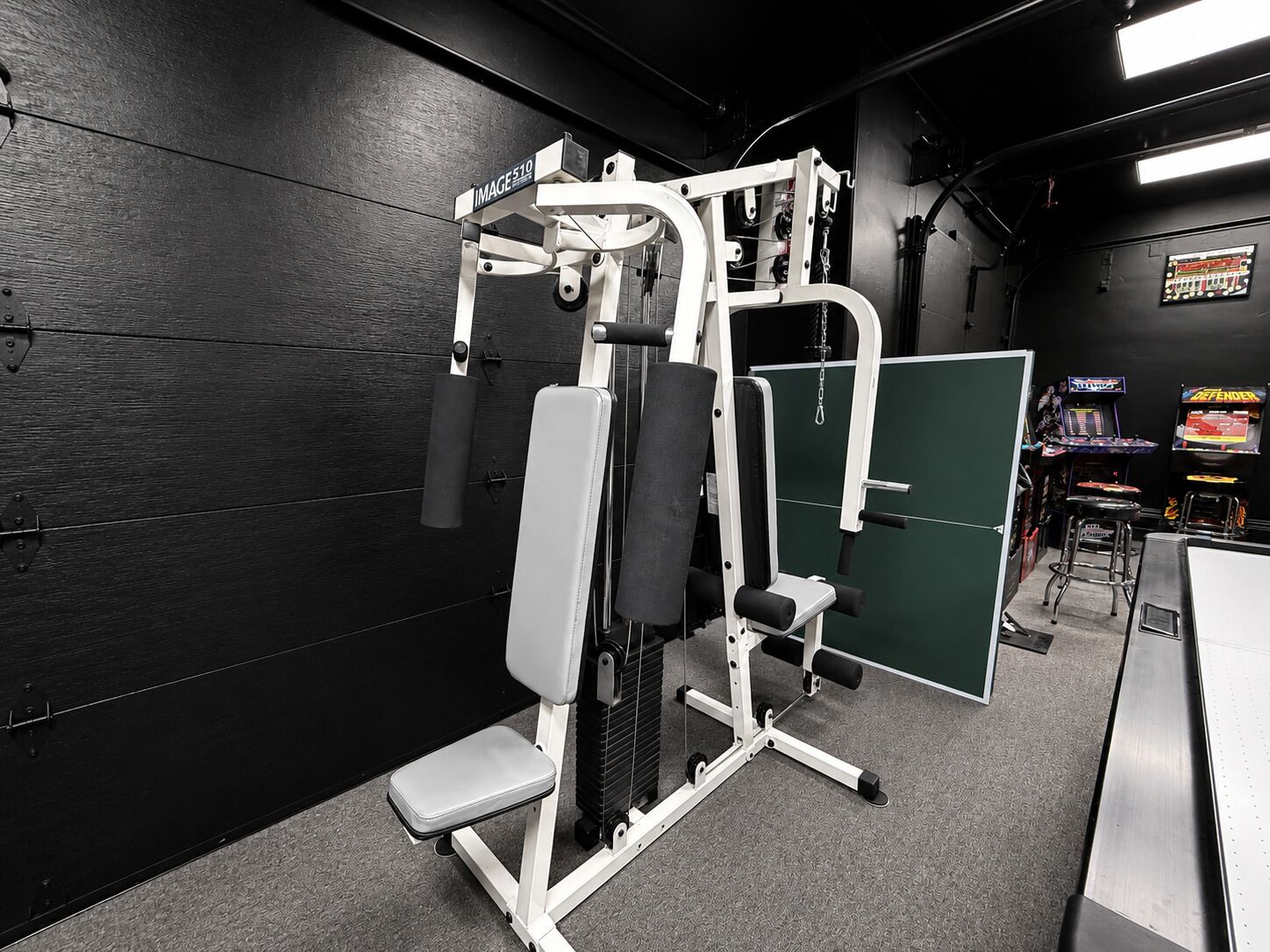 A gym with a weight bench, a squat rack, and a bench press.