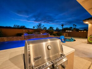 An outdoor grilling area with a pool and lounge chairs. - Exquisite 9BR/5BA Villa - Sports Court, Game Room, Movie Room, Pool, & Spa ★★★★★ (North Las Vegas)