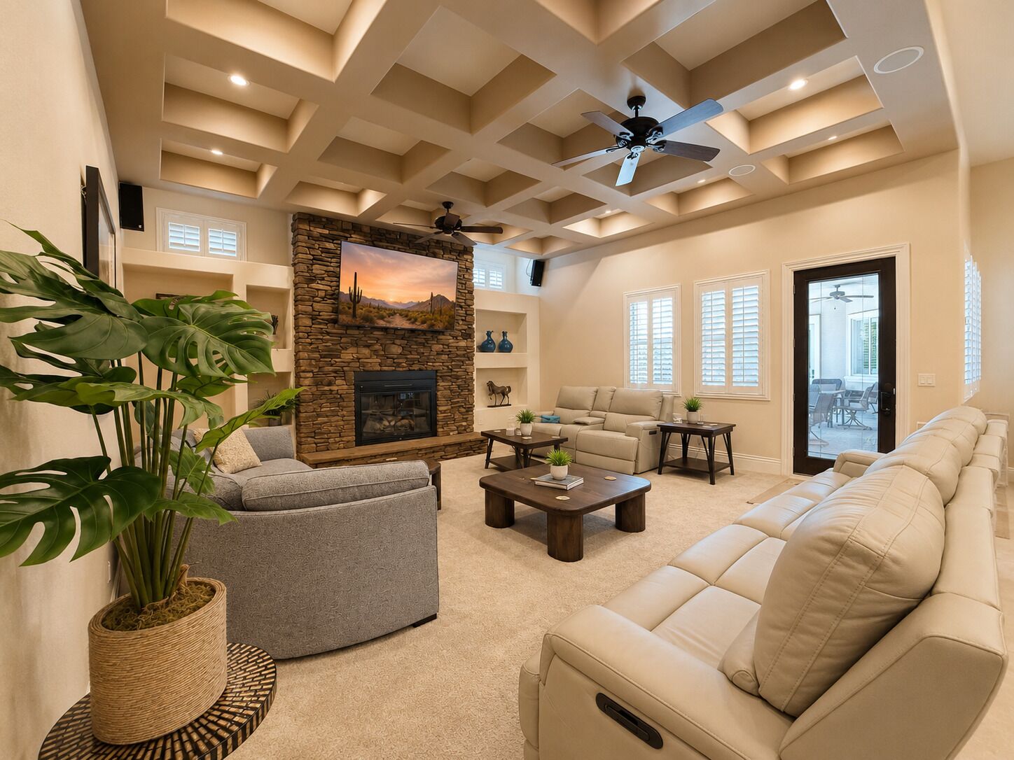 A living room with a stone fireplace, a ceiling fan, and a large window.