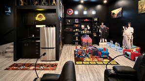 Um quarto com cozinha, área de estar com tapete temático de Star Wars e estantes com objetos de coleção.