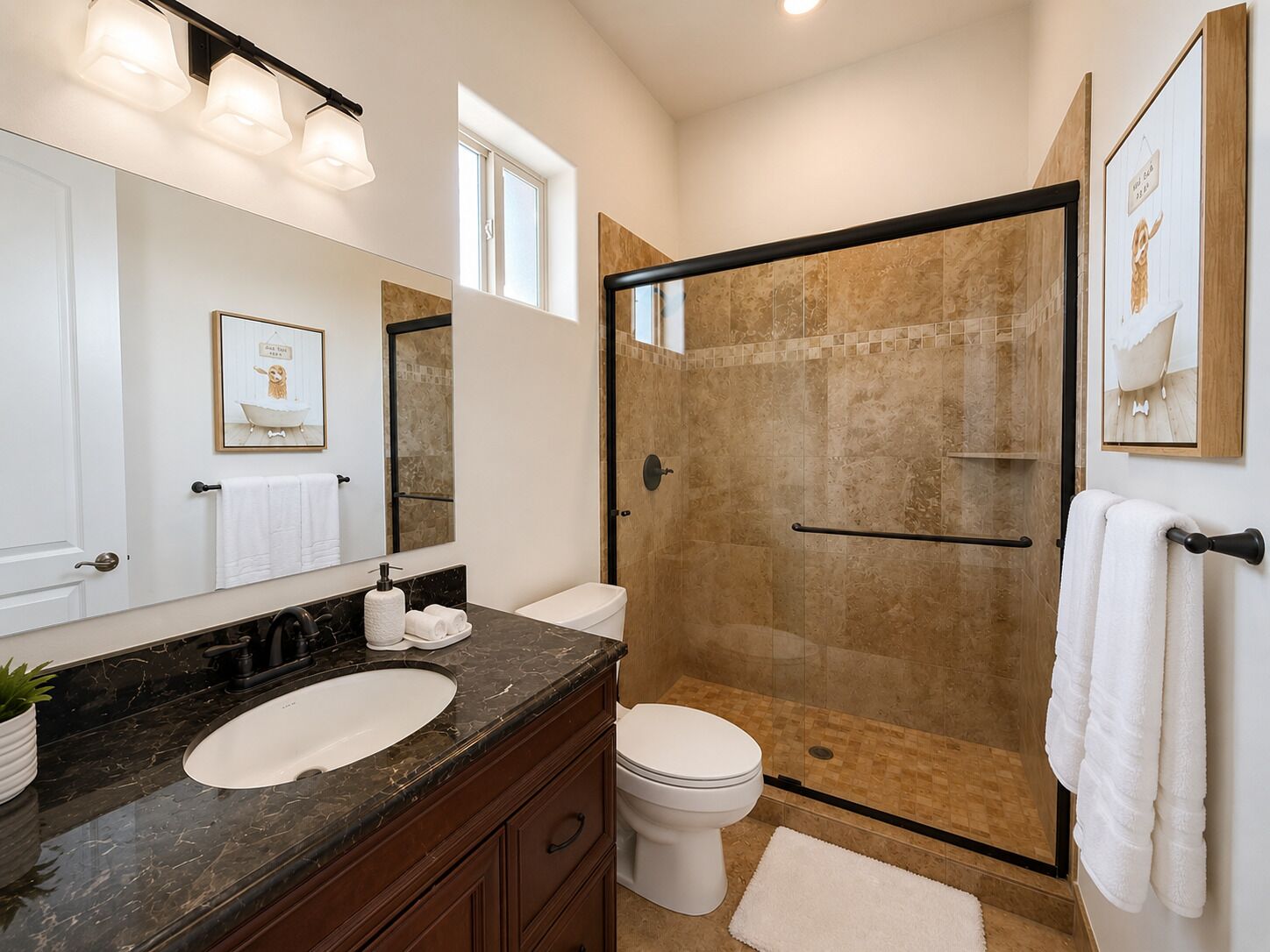 A bathroom with a marble sink, a toilet, a glass-enclosed shower, and a large mirror with wall-mounted lights.