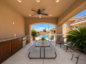 A covered patio with a pool, outdoor seating, and a ceiling fan. - Exquisite 9BR/5BA Villa - Sports Court, Game Room, Movie Room, Pool, & Spa ★★★★★ (North Las Vegas)