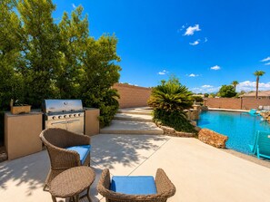 An outdoor pool area with a grill, wicker furniture, and a clear blue sky. - Exquisite 9BR/5BA Villa - Sports Court, Game Room, Movie Room, Pool, & Spa ★★★★★ (North Las Vegas)