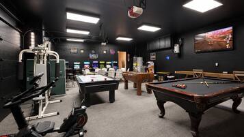 Une salle de loisirs équipée d’une table de billard, d’un baby-foot, d’appareils de musculation et de jeux d’arcade.