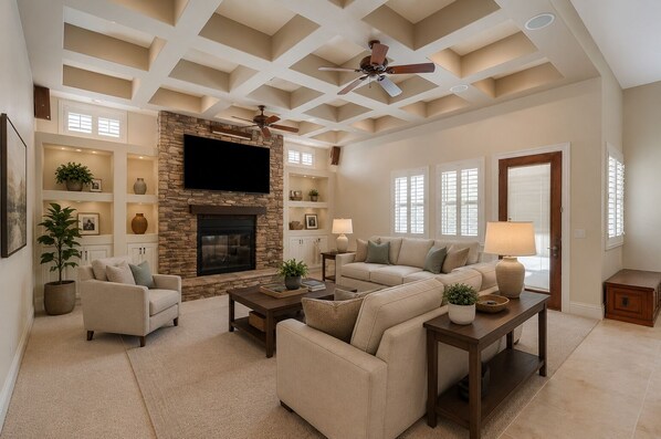 A living room with a fireplace, sofas, a coffee table, and a ceiling fan. - 8BR / 5BA Exquisite Villa - Beach-Entry Pool, Spa, Pickleball ★★★★★ (North Las Vegas)
