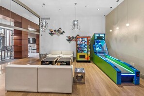 Et moderne loungeområde med sofa, sofaborde, en automater og en bowlingbane.