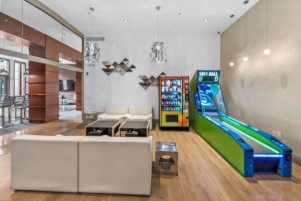 Een moderne loungeruimte met een bank, salontafels, een automaat en een bowlingbaan.