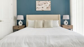 Een netjes opgemaakt bed met twee nachtkastjes, elk met een lamp, in een kamer met een blauwe wand en een lijstwerk erboven.