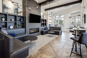 Ein modernes Wohnzimmer mit Kamin, großem Fernseher und einem Essbereich mit Tisch und Stühlen.