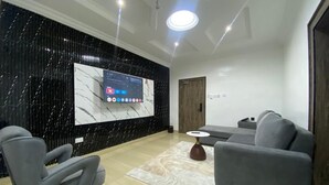 Una sala de estar moderna con un televisor de pantalla plana, sofás grises, una mesa de centro y una pared de mármol.